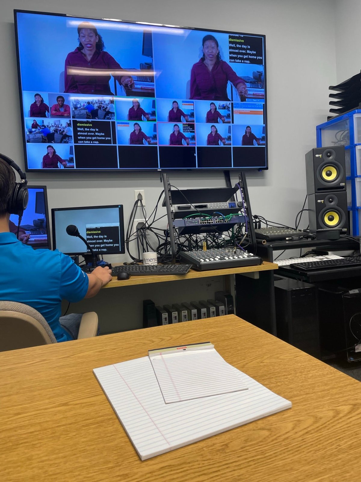 Researcher in a control room recording a simulated conversation shown across multiple monitors