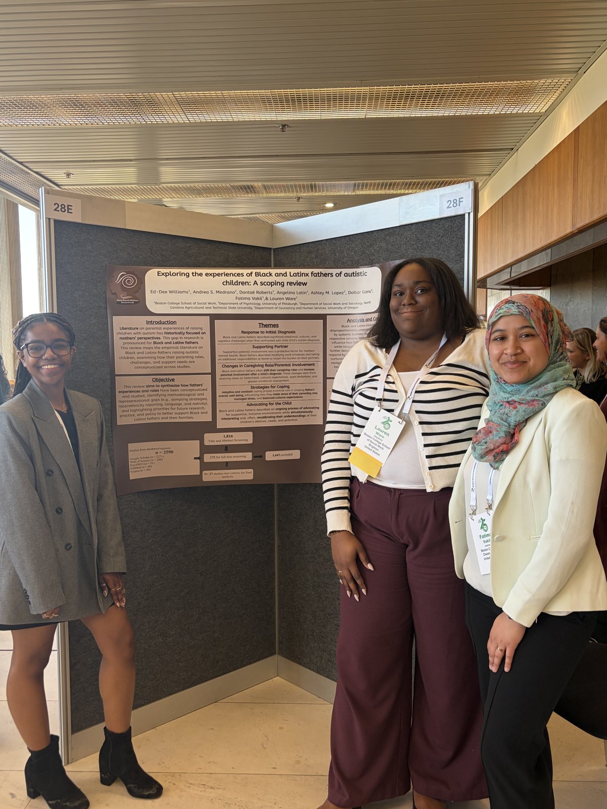 Three student researchers standing beside their conference poster on Black and Latino fathers of autistic children